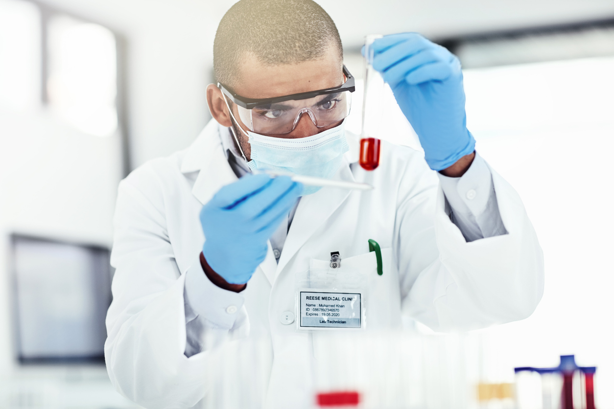 Scientist With Mask Holding a Vial of Blood